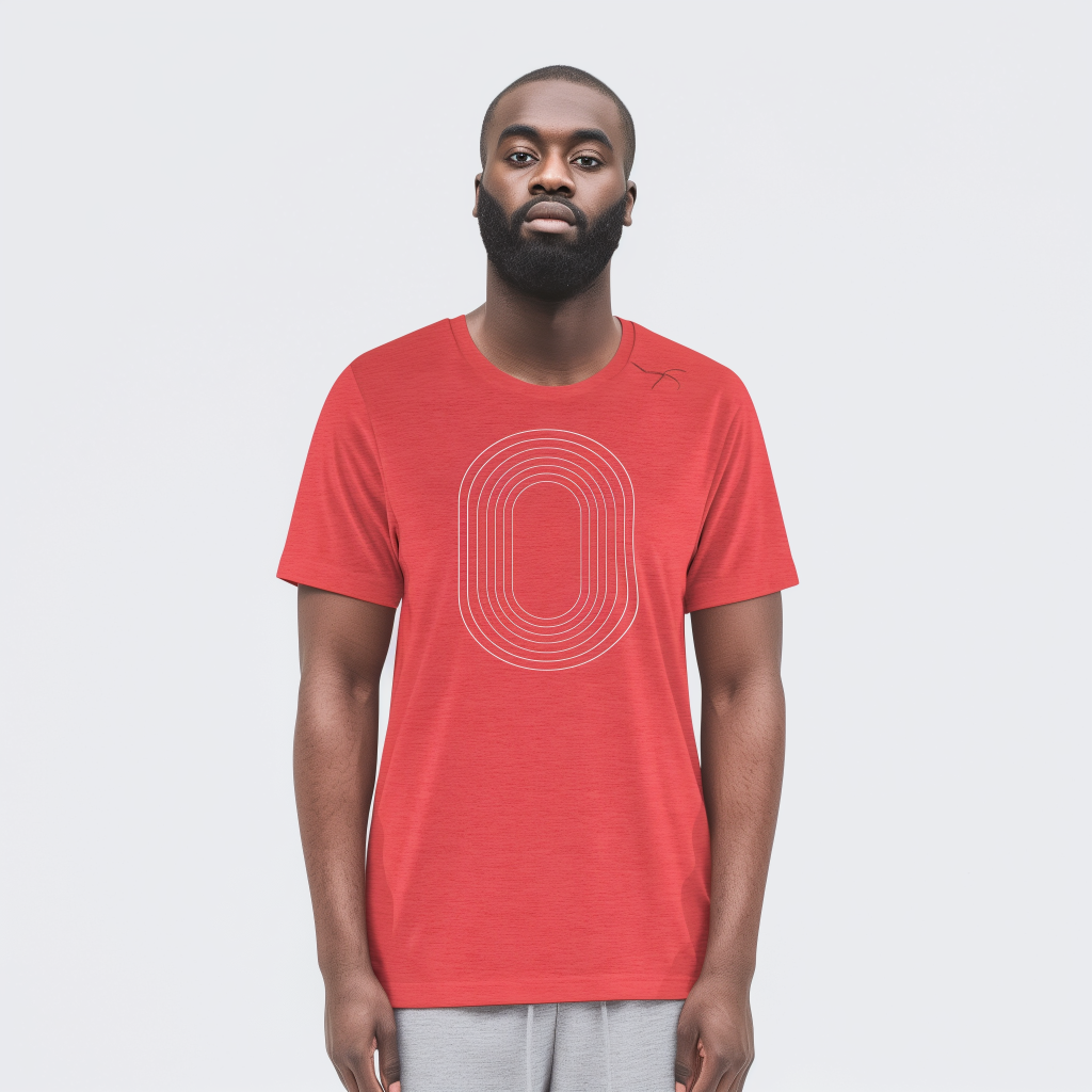 Man with short hair and a full beard standing against a pale background, wearing a red t-shirt printed with thin white concentric oval lines and light gray pants, facing the camera with a neutral expression.