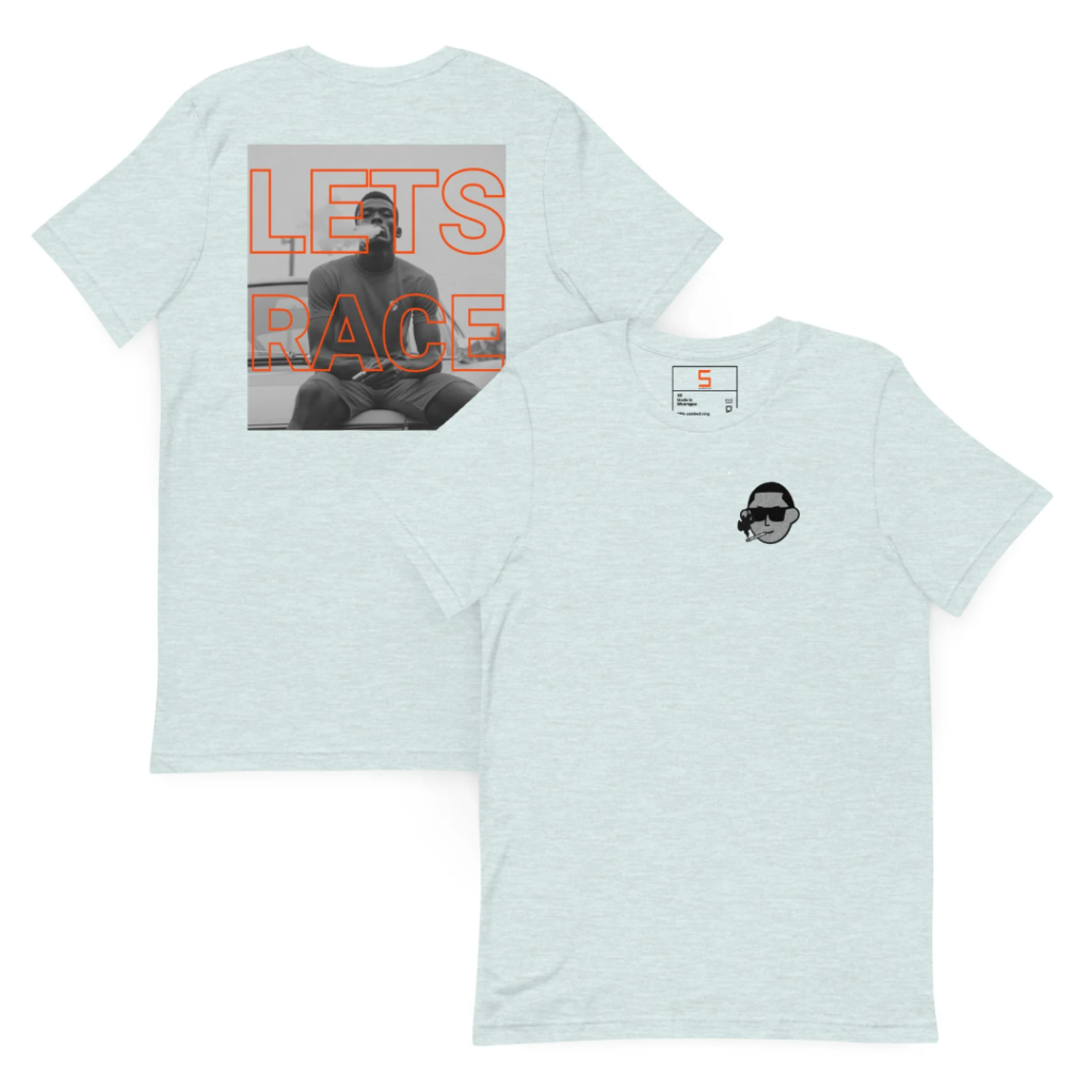 Two light heather-blue T-shirts shown overlapping to display back and front; the back has a large black-and-white photo of a seated man overlaid with bold orange outlined text reading LETS RACE, and the front has a small black graphic of a man's head smoking with a size label near the collar.
